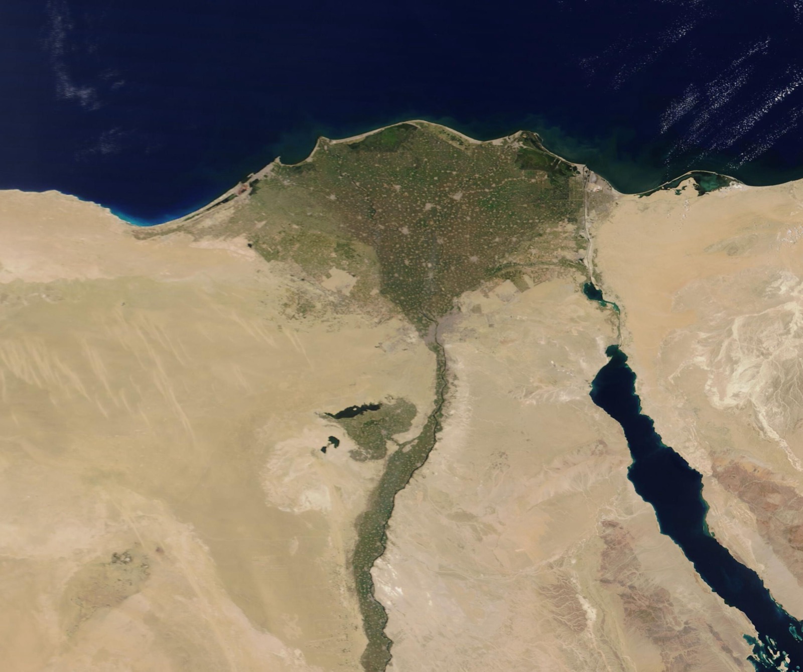 A satellite view of northern Egypt. A thin green ribbon of river runs north through tan desert, then fans out into a broad green triangle that meets the dark blue Mediterranean; the Red Sea and Sinai sit to the right